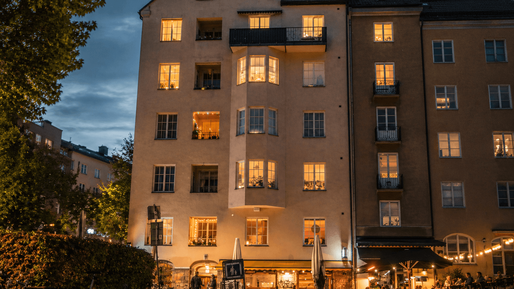 Bostadshus med upplysta fönster och gatuliv kvällstid